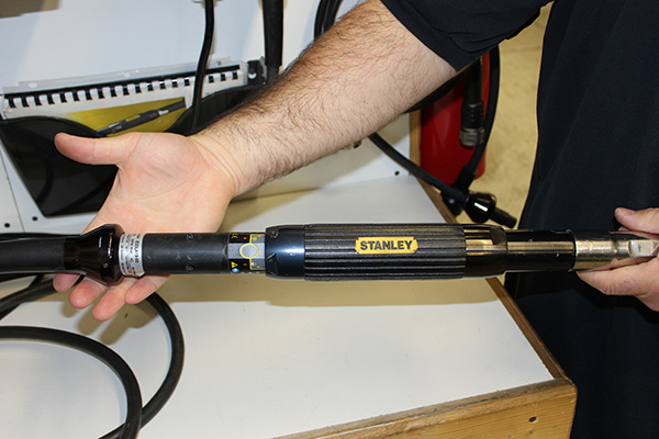 A technician holding a black E33 600 nutrunner made by Stanley