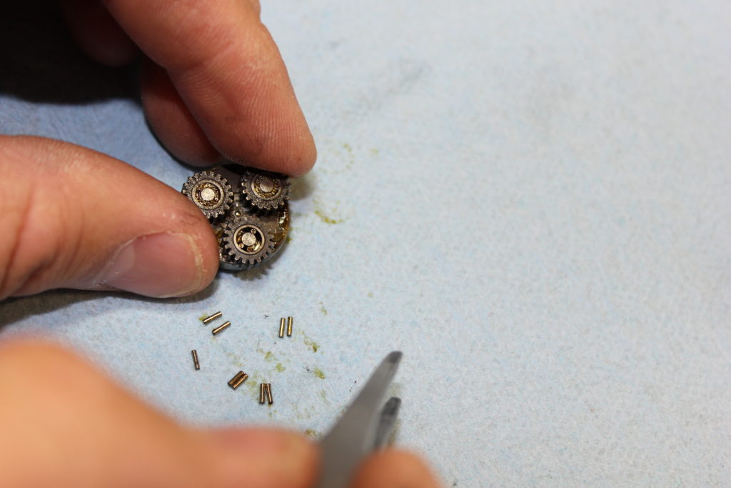 A planetary gearbox is being cleaned and lubricated. There are 9 needle rollers that have been removed from the gearbox.