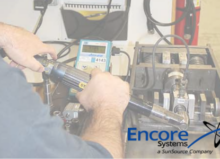 An Encore Systems employee calibrating an assembly tool with Encore's logo in the bottom right corner