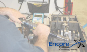 An Encore Systems employee calibrating an assembly tool with Encore's logo in the bottom right corner